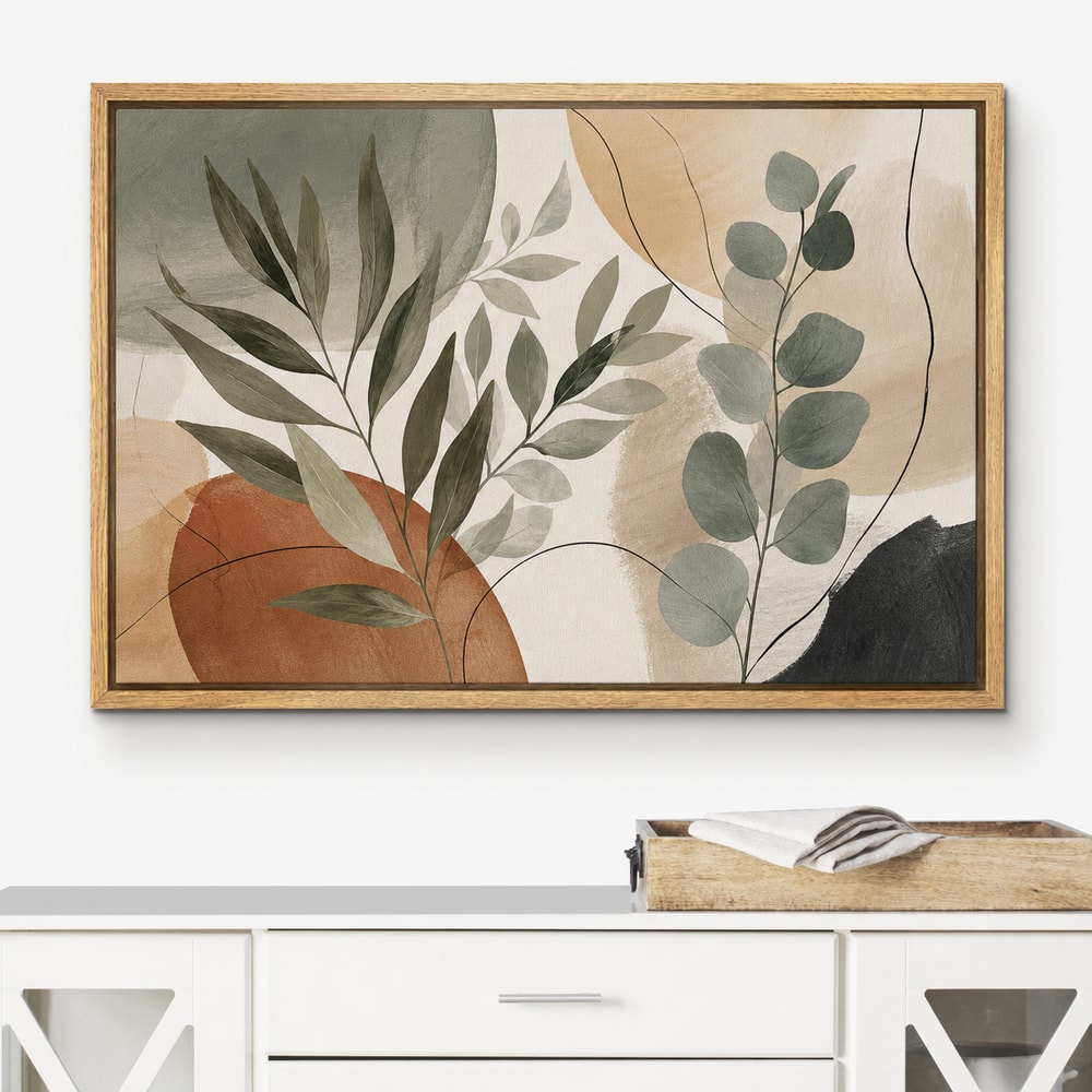 Earth-tone botanical artwork displayed in a pecan floating frame above a white console